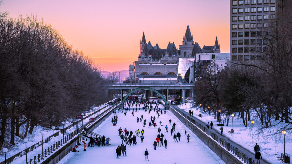 "Skaters enjoying the Rideau Canal locks Skateway at sunset in Ottawa with Château Laurier in the background."